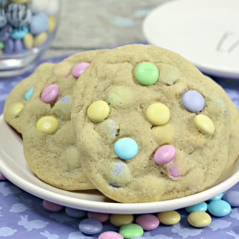 Large cookies with pastel M&Ms, served on a white plate.