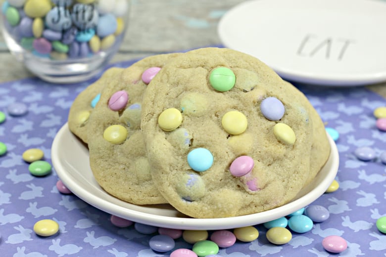 Large cookies with pastel M&Ms, served on a white plate.