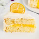 Slice of lemon layer cake with lemon curd filling and marshmallow frosting.