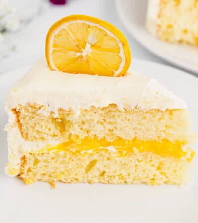 Slice of lemon layer cake with lemon curd filling and marshmallow frosting.