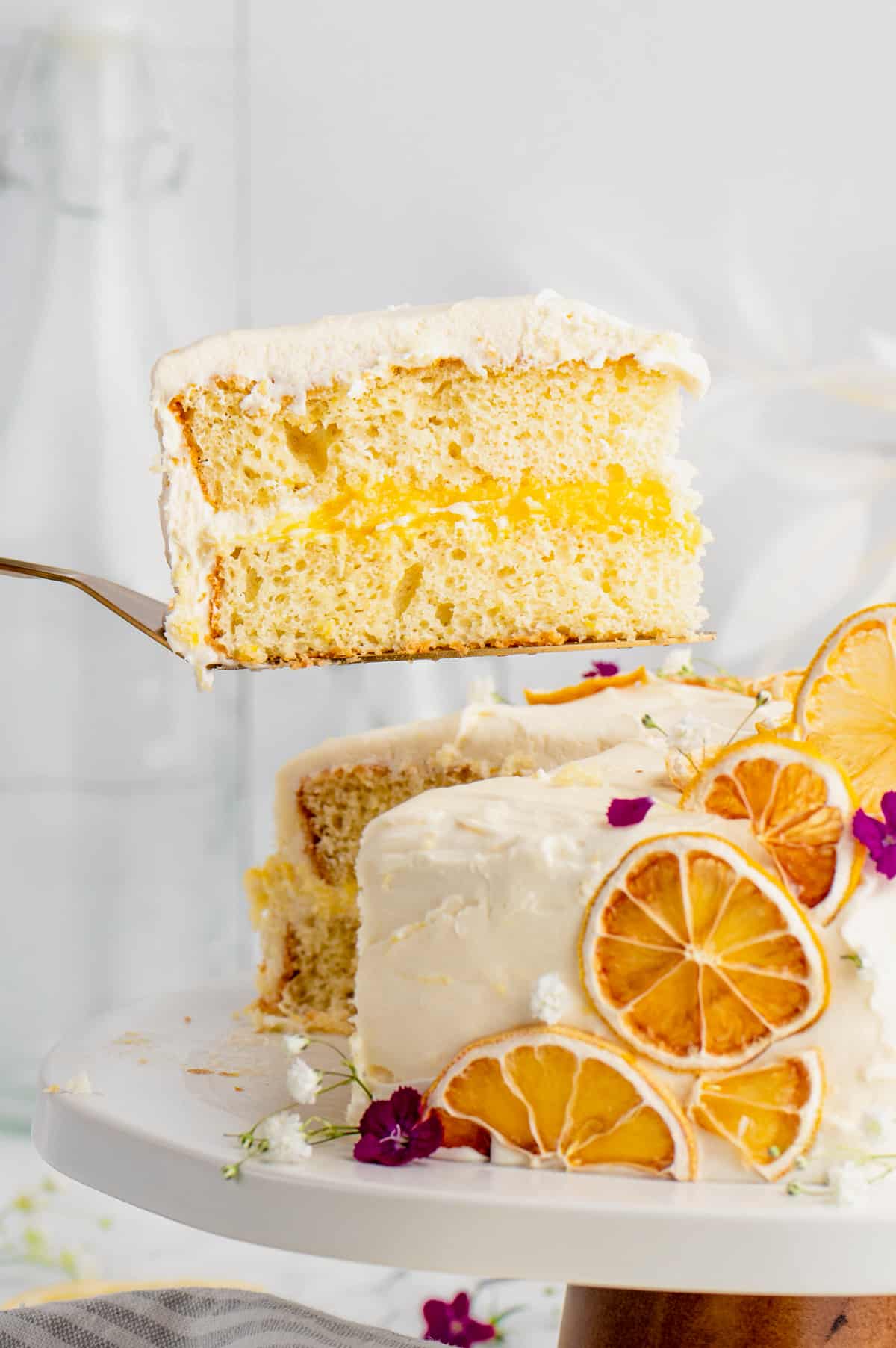 Slice of lemon curd cake being removed from cake with a cake server.