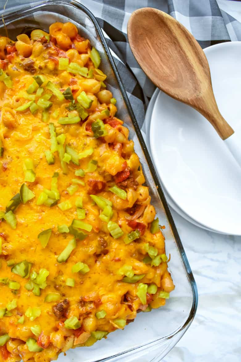 A hearty and family-friendly 40-minute cheeseburger casserole recipe made with ground beef, macaroni, cheddar cheese, onions, tomatoes, and dill pickles.