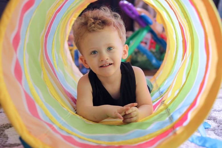 Toddler boy crawling through toy tunnel