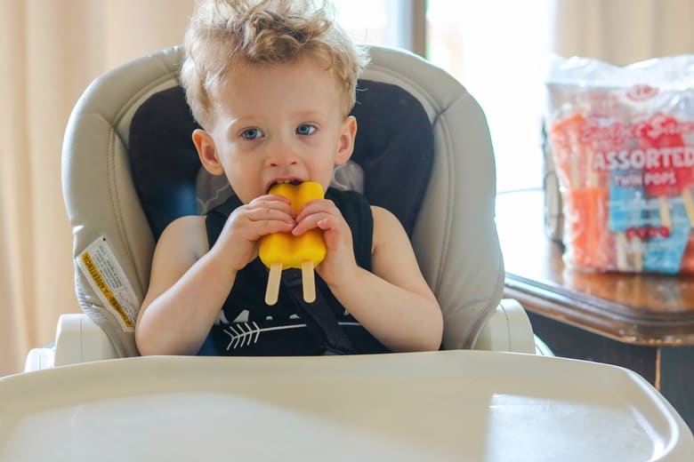 Toddler boy in highchair eating Twin Pops