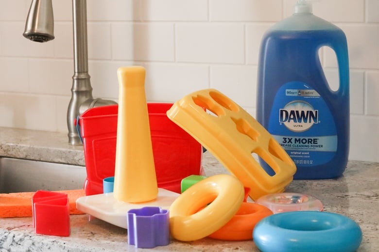 Plastic toys on countertop with bottle of Dawn dish soap and sink in background