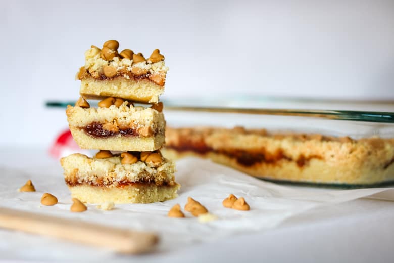 Peanut butter and jelly cookie bars stacked next to baking pan