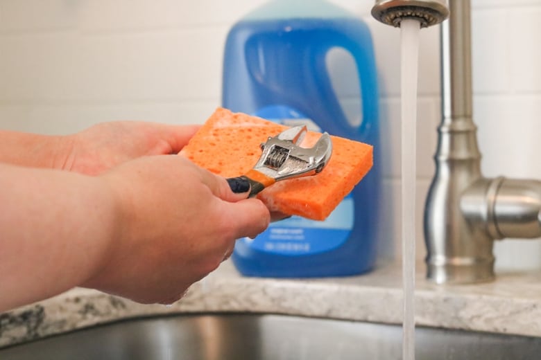 Wrench being wiped with a sudsy sponge