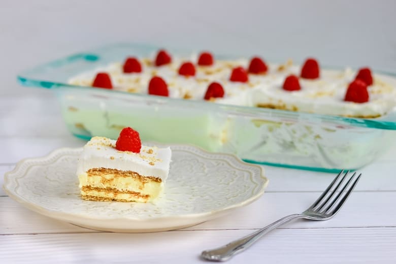 Slice of lemon pudding cake on a plate next to cake dish.