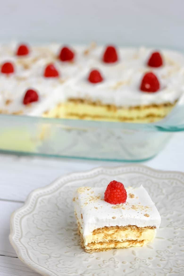 Slice of lemon pudding cake on a plate next to cake dish.