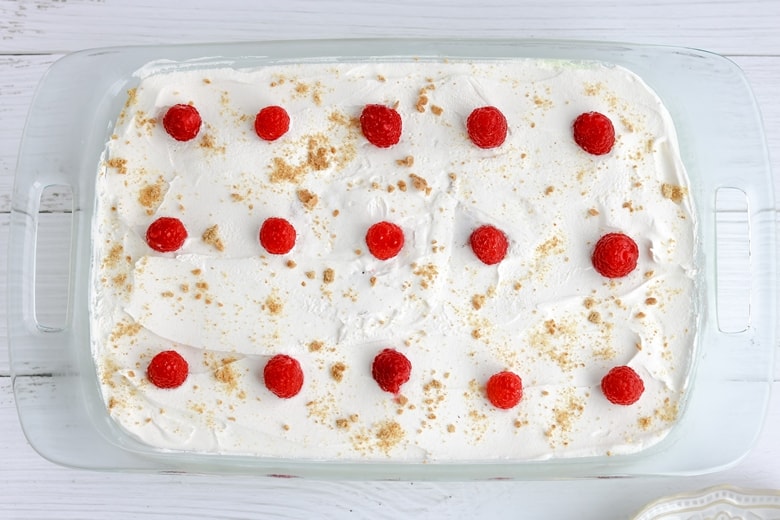 9 x 13 glass baking dish with lemon cake topped with raspberries