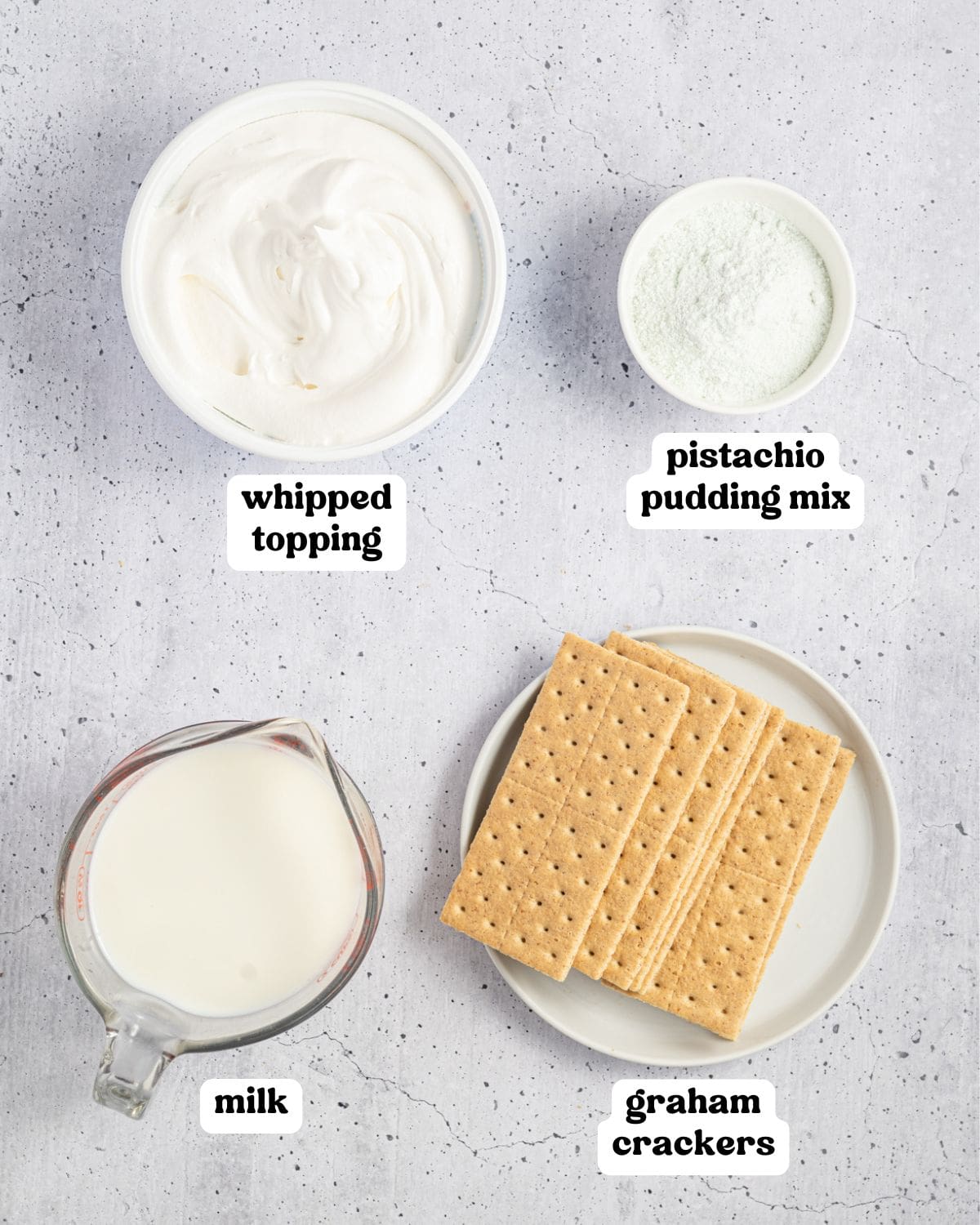 Labeled ingredients for pistachio icebox cake, including whipped topping, pistachio pudding mix, milk, and graham crackers.