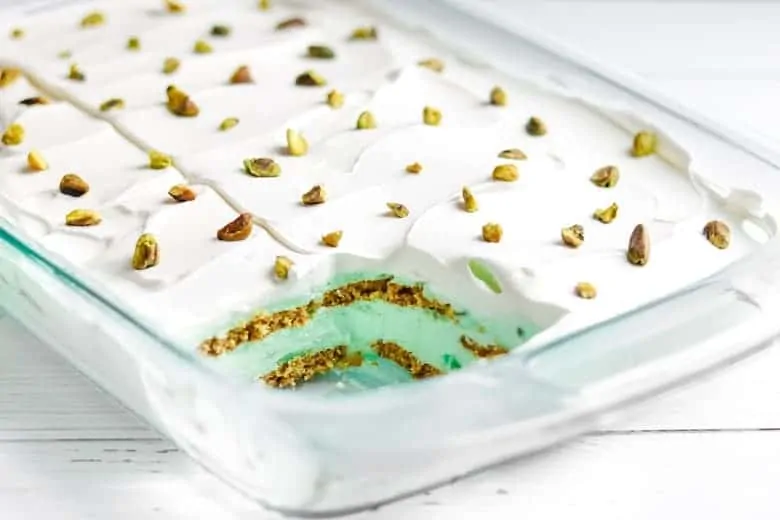 Pistachio layered dessert in 9 x 13 glass pan with layers of pistachio pudding, graham crackers, and cool whip.
