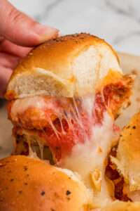 A chicken parm slider with nuggets and melty cheese being pulled from the pan.
