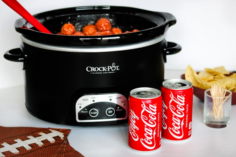 Crockpot Meatballs with Coca-Cola served in crockpot with cans of coke and chips