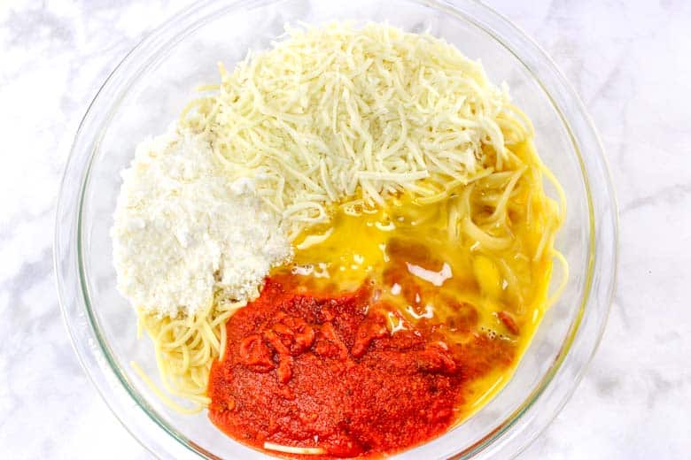 spaghetti, cheese, marinara, egg in glass mixing bowl
