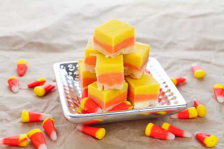 Candy Corn Fudge on silver platter, with candy corn sprinkled around the table.