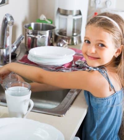 Young girl washing dishes in a sink