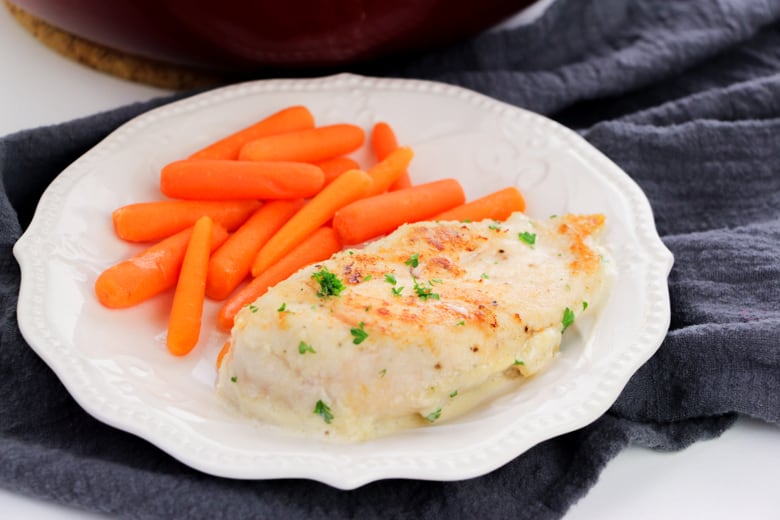 Creamy Garlic Chicken and carrots on white plate with dark blue napkin