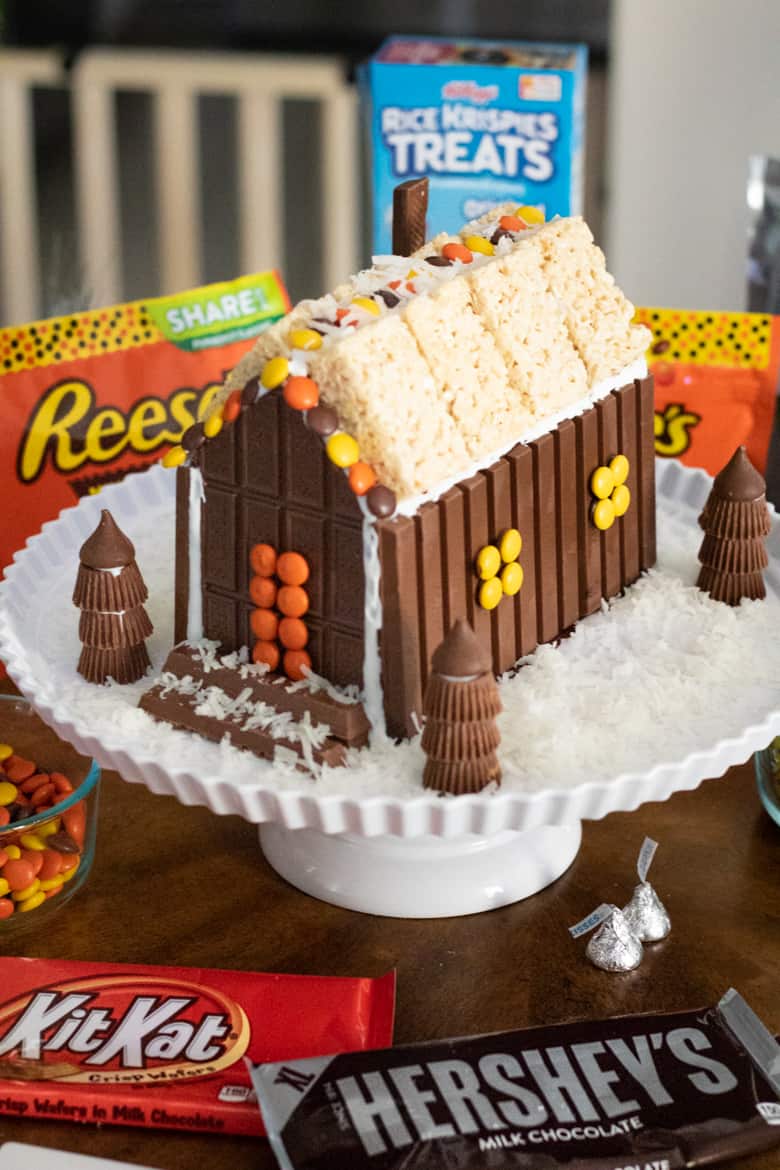 Christmas candy house made with chocolate bars, kit kats, reese's peanut butter cups, kisses, and rice krispie treats.