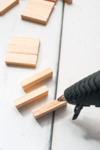 Hot glue gun applying glue to wood blocks