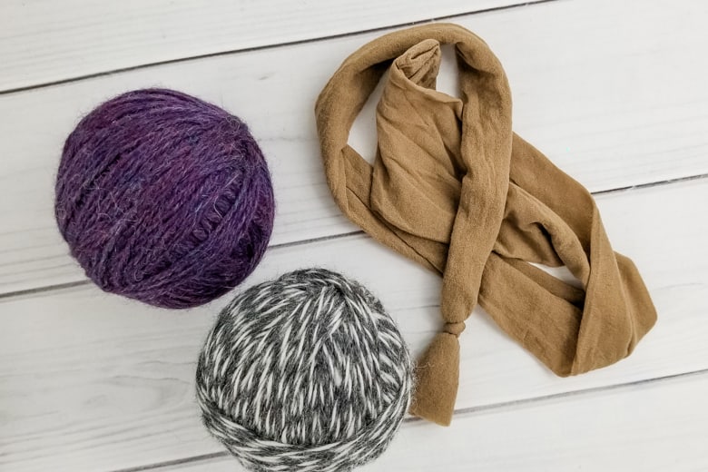 Scissors cutting the yarn and a crochet hook tucking the yarn end into a finished wool ball