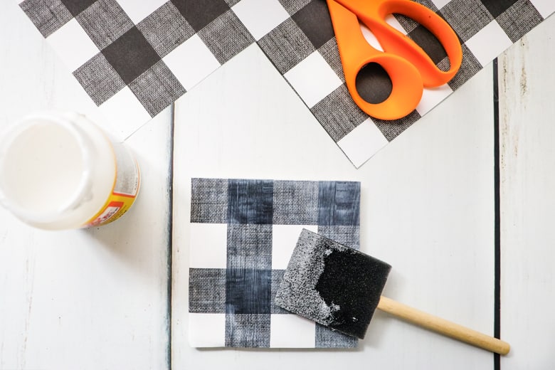 Foam brush applying Mod Podge on top of scapbook paper