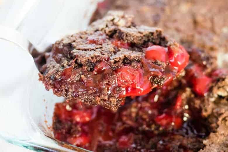 Chocolate cherry dump cake being scooped up with serving spoon.
