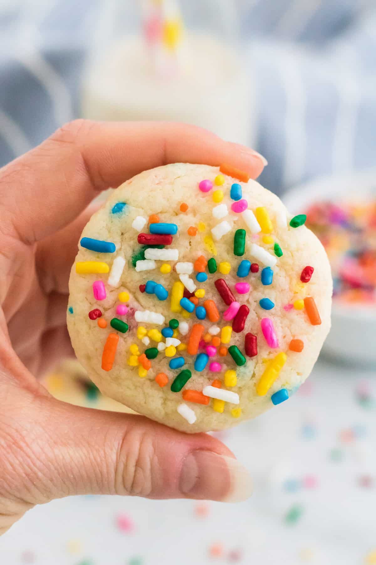 Hand holding rainbow sprinkle funfetti cookie made with cake mix.