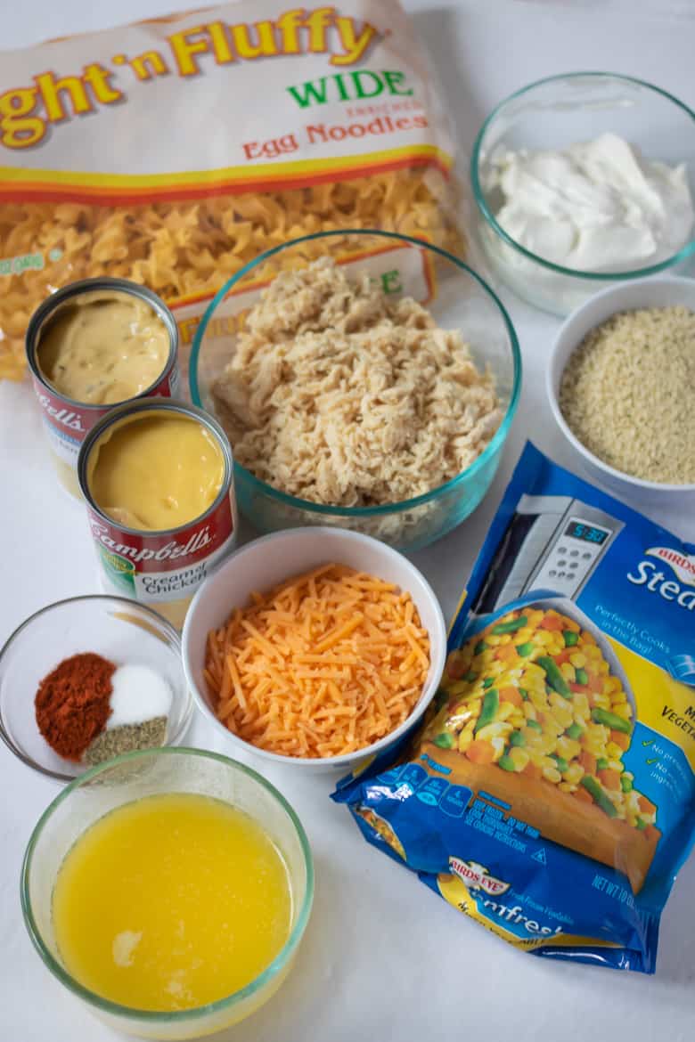 Chicken Noodle Casserole Ingredients: frozen mixed vegetables, shredded chicken, egg noodles, cream of chicken soup, shredded cheese, bread crumbs, sour cream, melted butter, and seasonings