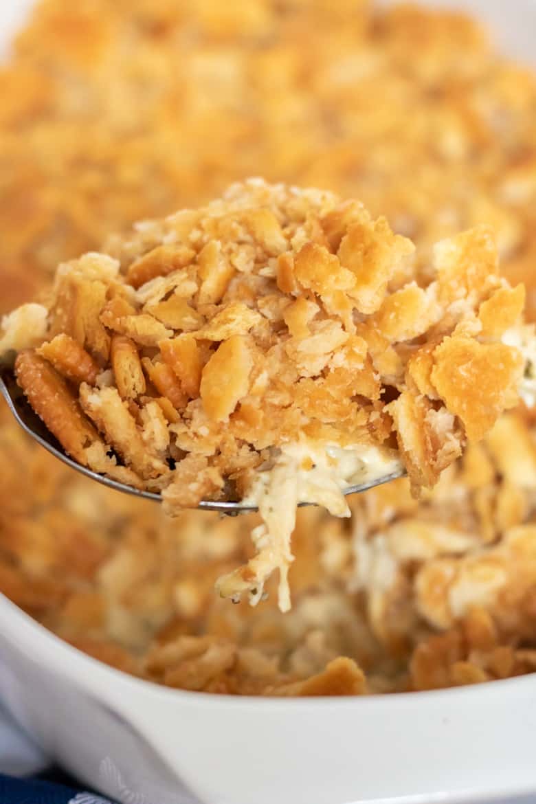 Chicken Ritz Casserole being spooned out of baking dish. It is topped with lots of buttery ritz cracker pieces.