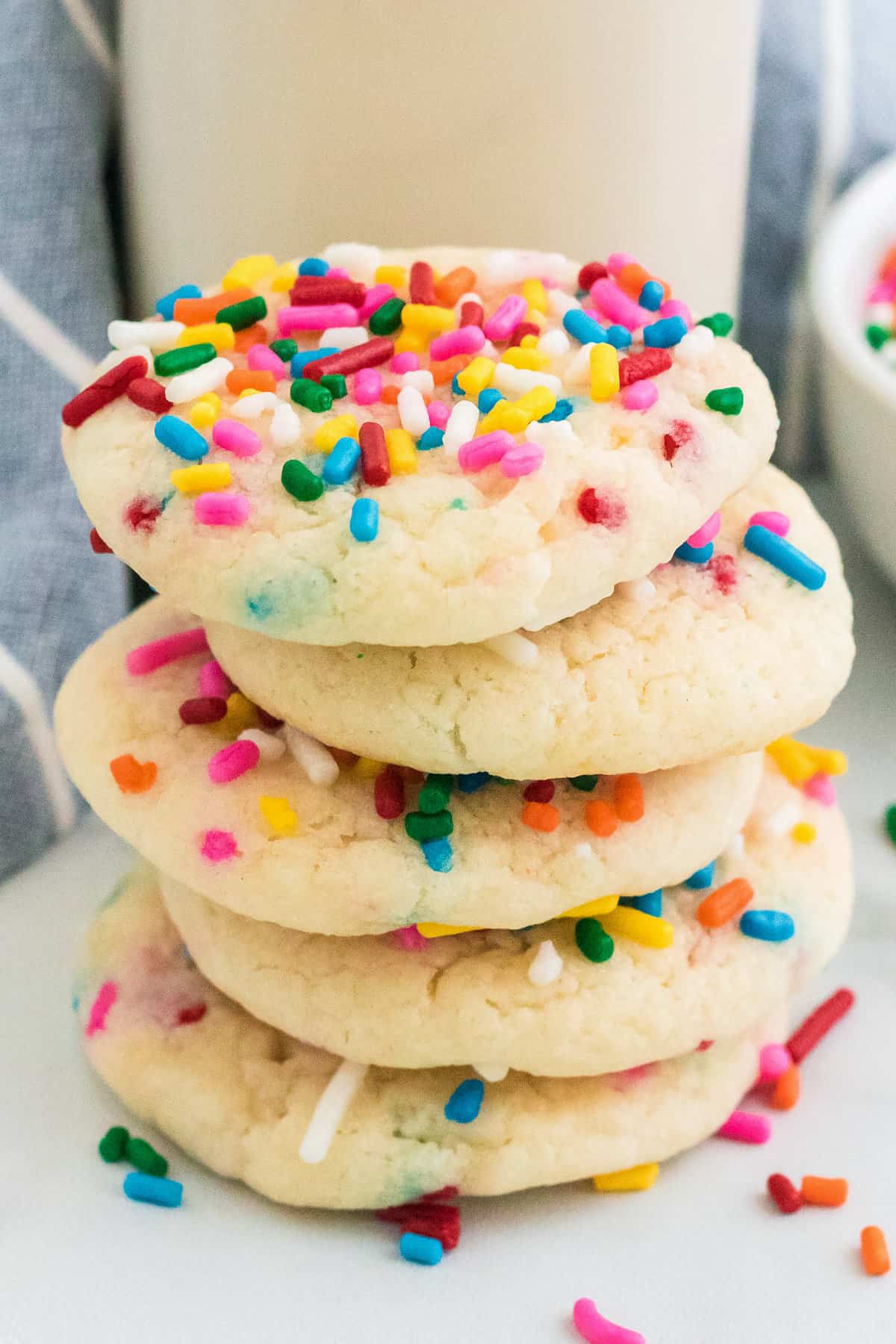 Stack of funfetti cake mix cookies with sprinkles next to a glass of milk.