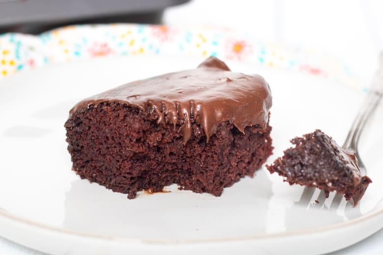 Moist crazy chocolate cake with chocolate frosting. A fork has taken a piece out of the cake and is resting on the plate.