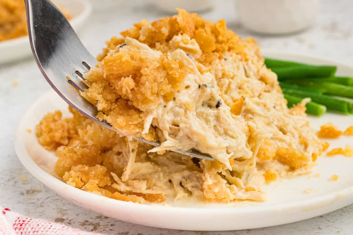 Fork taking fokfull of creamy ritz cracker chicken casserole off of plate. 