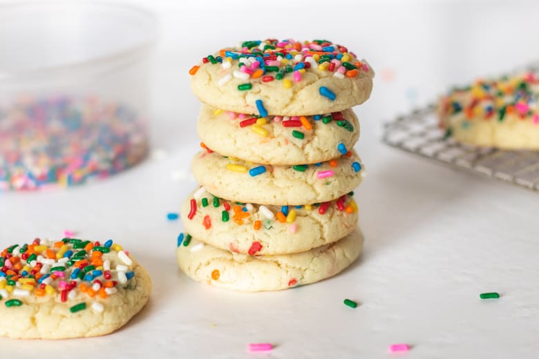Funfetti Cookies from cake mix stacked one top of one another with rainbow sprinkles and additional cookies in the background.