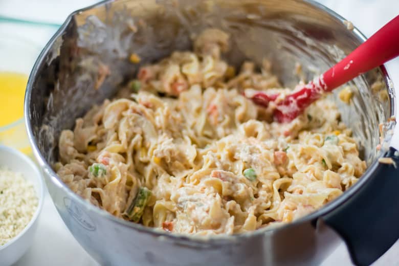 Chicken Casserole Ingredients being mixed in a large bowl with a red spoon