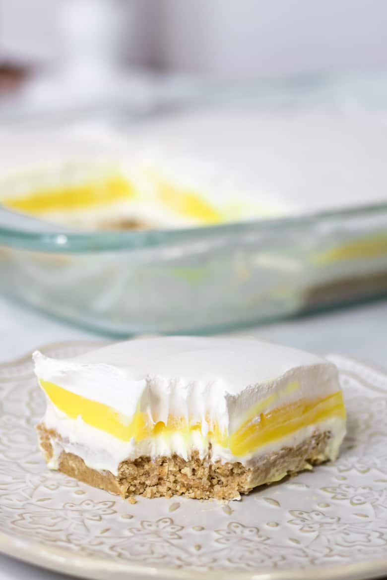 Lemon Lush layered dessert on plate with fork marks from a bite being taken out