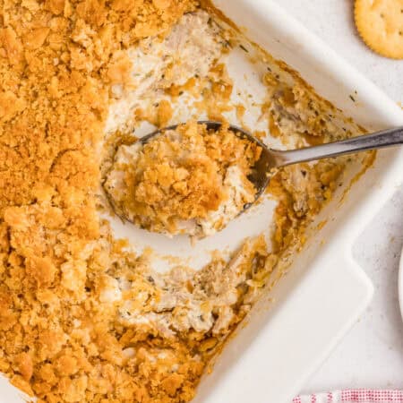 Serving spoon in rectangular ritz casserole with shredded chicken.