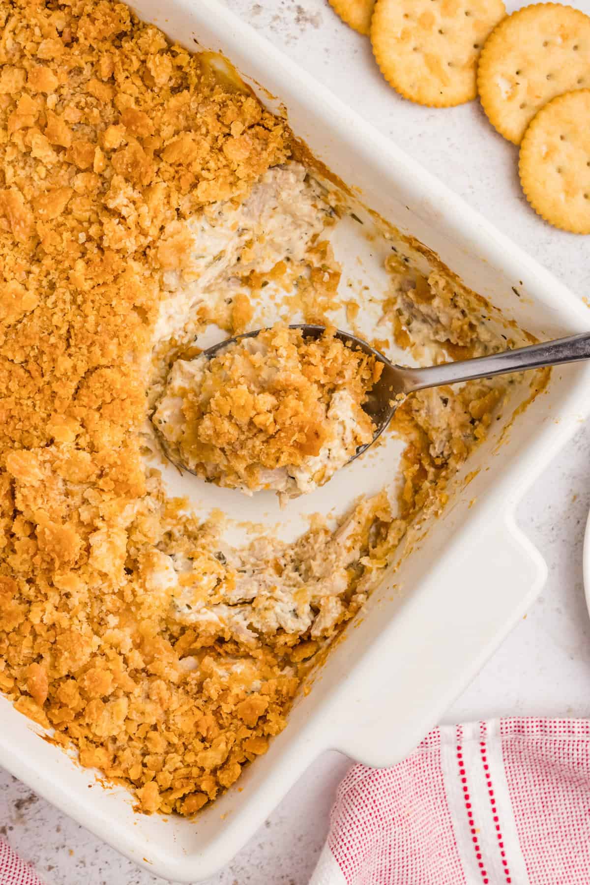 Serving spoon in rectangular ritz casserole with shredded chicken.