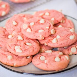 Strawberry cake mix cookies with white chocolate chips on a white plate.