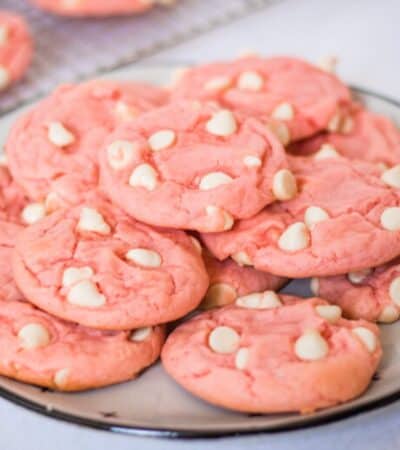 Strawberry cake mix cookies with white chocolate chips on a white plate.
