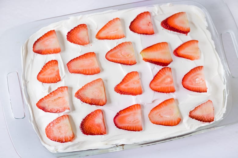Strawberry jello Cake with whipped topping and fresh sliced strawberries.