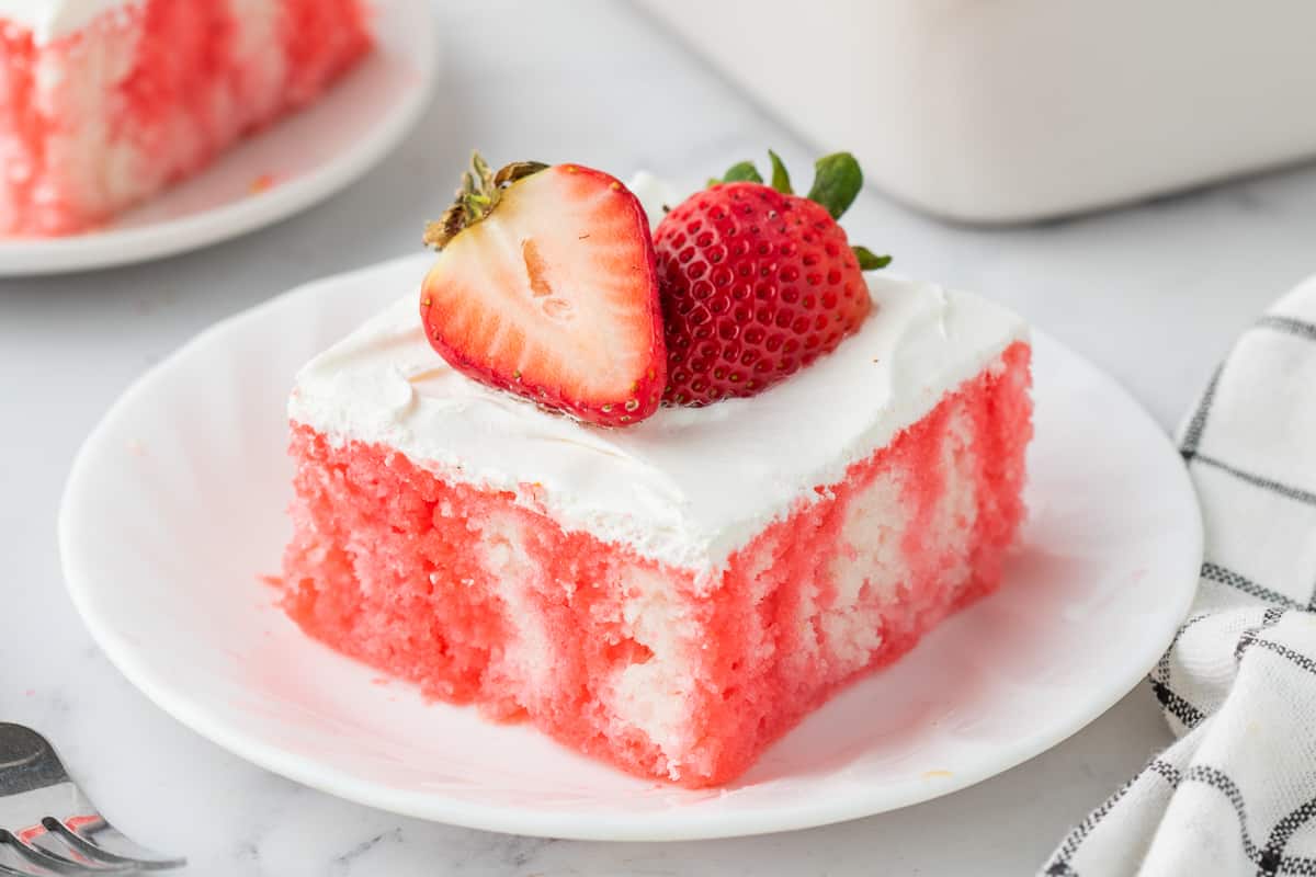 Strawberry jello poke cake with cool whip and fresh berries.