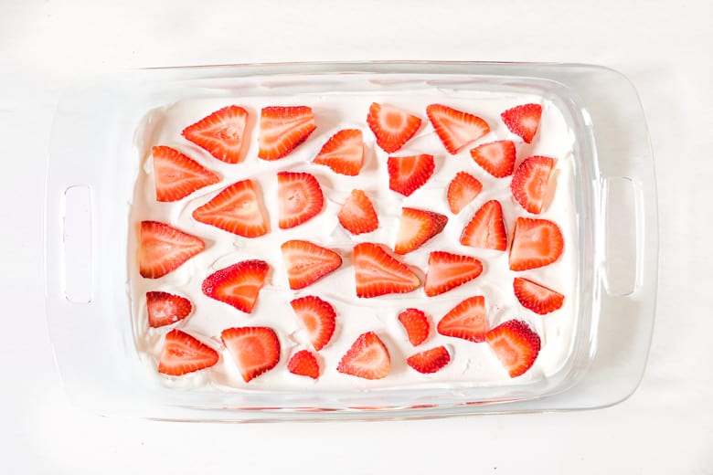 Cool Whip topped with sliced strawberries in a glass pan