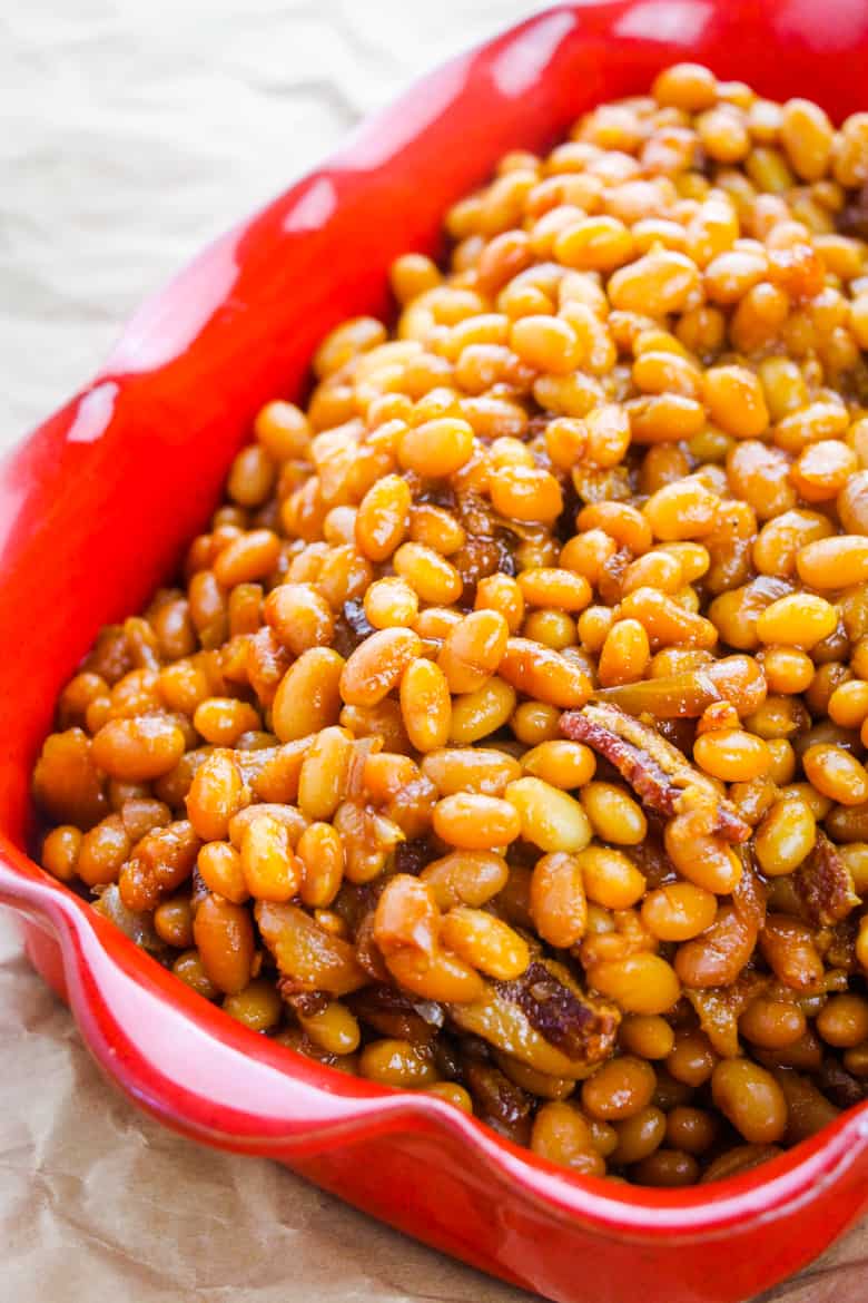 Boston baked beans with onions and bacon in a red rectangular casserole dish.