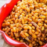 Boston baked beans with bacon in a red dish.