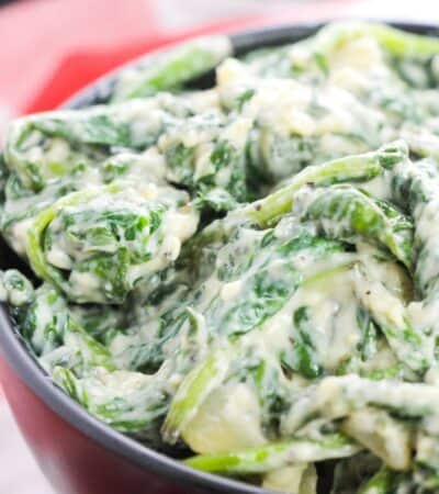 Creamed spinach with a creamy white sauce in a black bowl