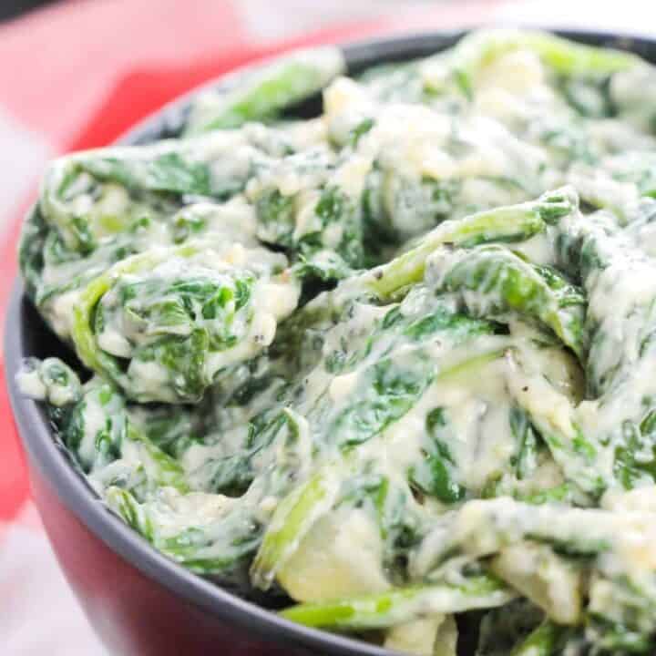Creamed spinach with a creamy white sauce in a black bowl