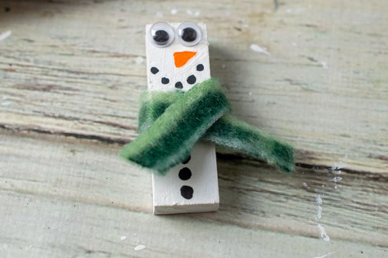 Wood block painted to look like snowman with a piece of fabric glued on to look like scraft