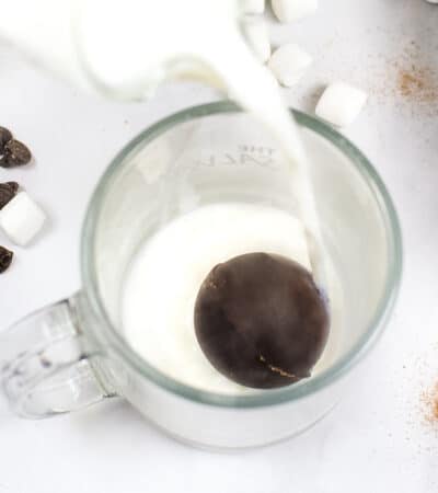 Hot Chocolate Bomb in glass with milk being poured over it