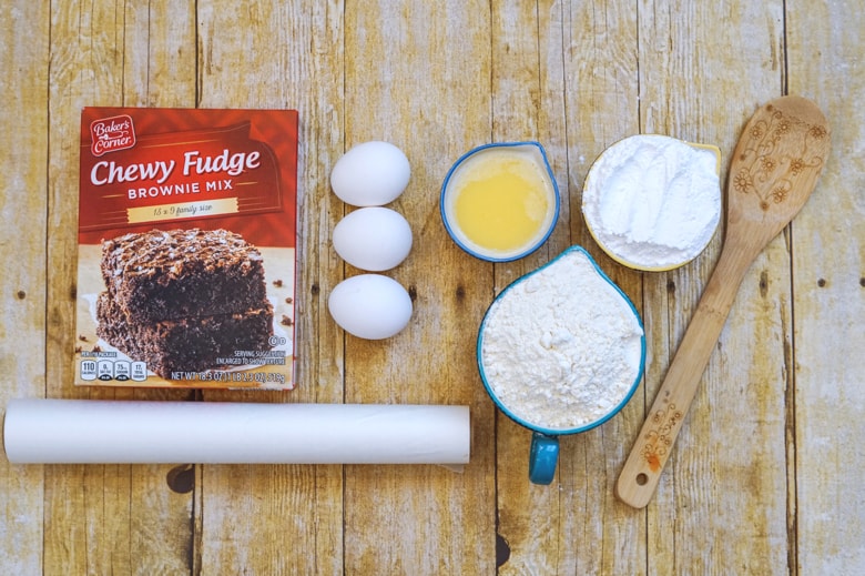 Brownie mix, 3 eggs, melted butter, flour, powdered sugar, parchment paper and wooden spoon